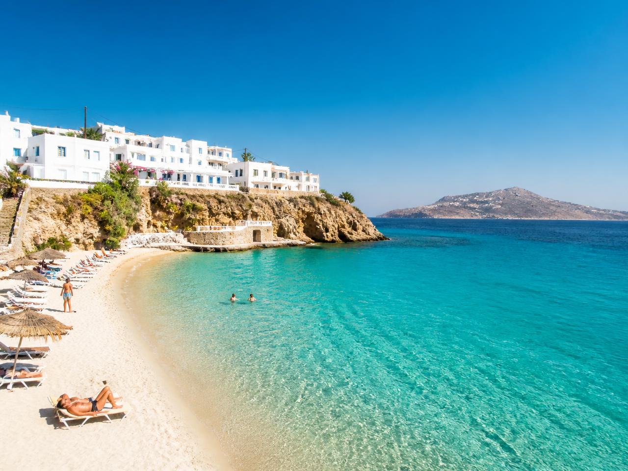 Whitewashed cliffside village with blue domes above the deep blue Aegean sea in Santorini, Greece